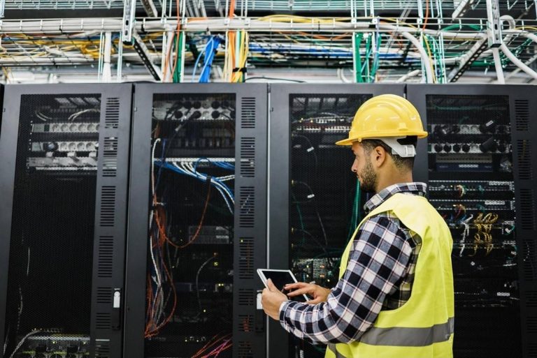 Engineer in hard hat inspecting server racks during an IT infrastructure upgrade